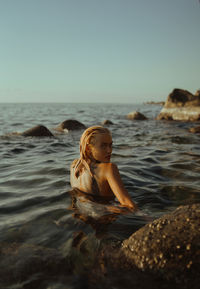 Rear view of woman swimming in sea against clear sky