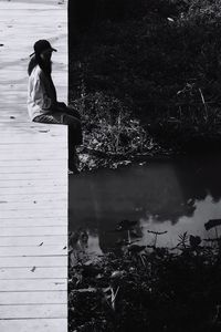 Side view of woman sitting by lake