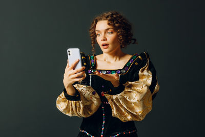 Portrait of young woman standing against black background