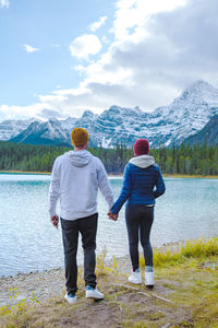 Rear view of couple walking on mountain against sky