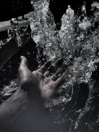 Cropped hand touching splashing water