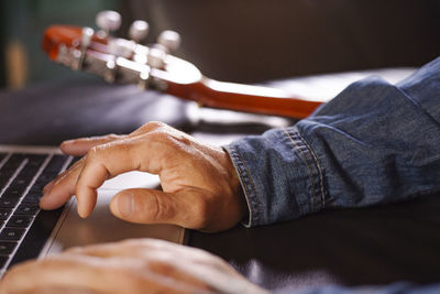 Man's hands looking for information on how to learn to play the guitar online