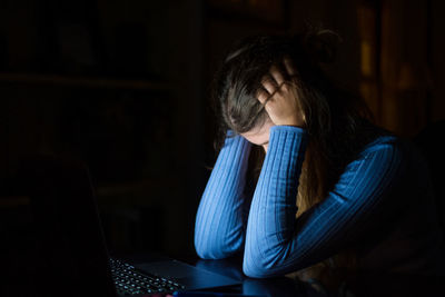 Side view of woman using laptop at home