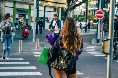 Rear view of people crossing road