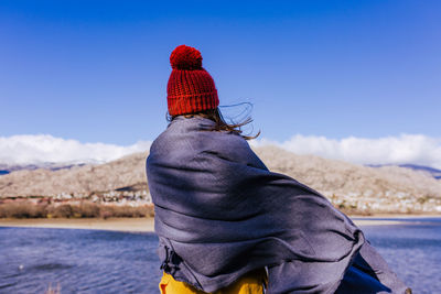 Rear view of woman with shawl standing by lake