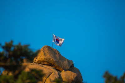 Flag on rock against clear blue sky