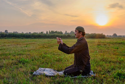 Side view of man using mobile phone on field