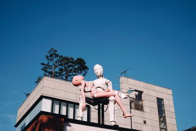 Low angle view of statue against building against clear blue sky