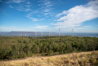 Wind turbines on field against sky