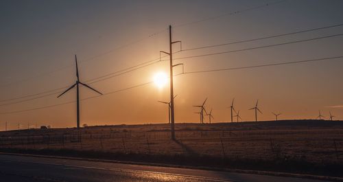 Silhouette of electricity pylon against sky during sunset