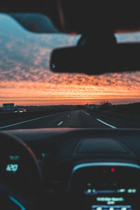 Road seen through car windshield during sunset