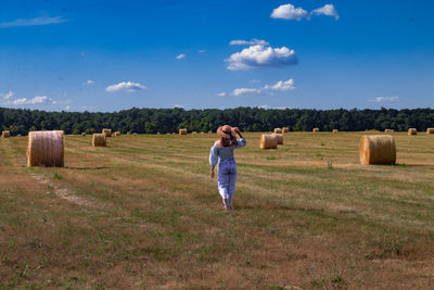 Background image of a young girl with a hat in a field with hay bales