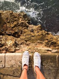 Low section of person standing on pier by sea