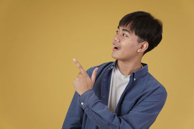 Boy looking away against yellow background