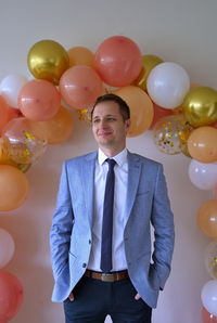 Portrait of businessman against balloons on the wall