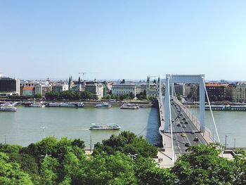 Bridge over river in city against clear sky