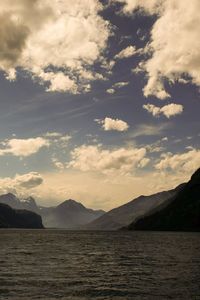 Scenic view of lake and mountains against cloudy sky