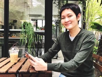 Portrait of smiling woman using mobile phone at cafe