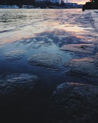 Surface level of wet river against sky during winter