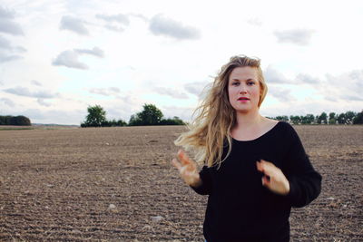 Portrait of beautiful young woman standing against sky