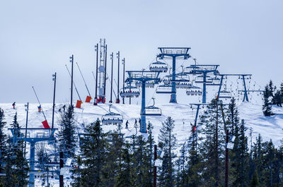 Ski lifts on snow covered mountain against sky