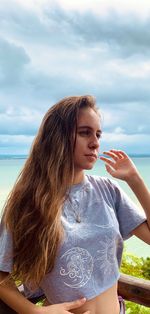 Beautiful young woman looking at sea against sky