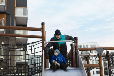 Friends sitting on railing against sky