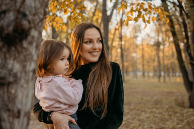 Ways to carry a toddler. close up outdoors portrait of happy family mom and toddler baby girl in