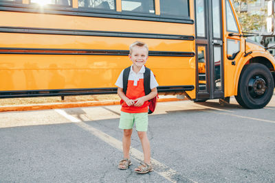 Smiling boy standing by bus