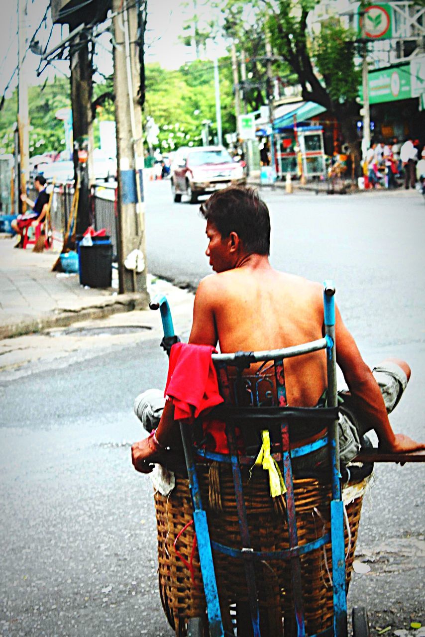 street, transportation, mode of transport, lifestyles, land vehicle, men, building exterior, city, incidental people, city life, car, leisure activity, person, built structure, rear view, architecture, sitting, casual clothing