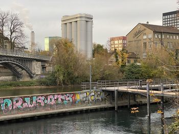 Bridge over river by buildings against sky