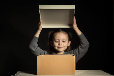 Portrait of woman holding box against black background