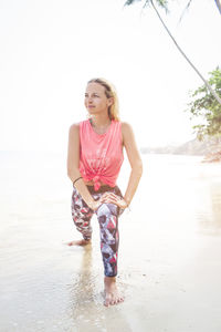 Full length of woman exercising on shore at beach