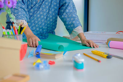 Midsection of woman with various objects on table