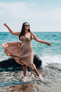 Young woman wearing sunglasses on beach against sky