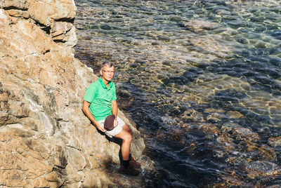 High angle portrait of man sitting on rock