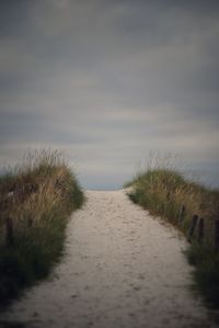 Footpath by road against sky