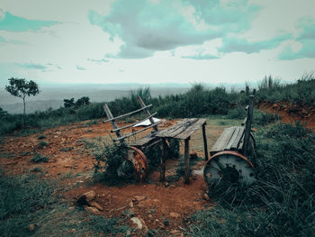 Abandoned cart on field against sky