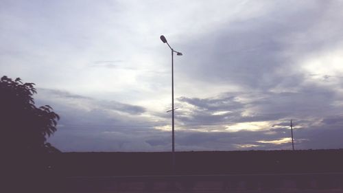 Low angle view of power lines against cloudy sky