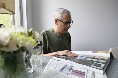 Man reading book while sitting on table at home