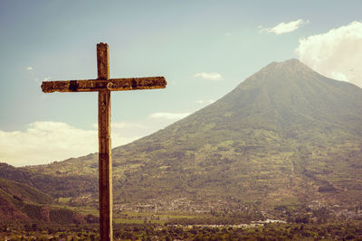 Cross on mountain against sky