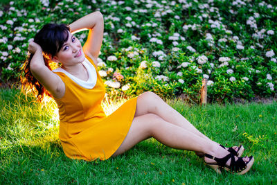 Side view of woman sitting on grassy field