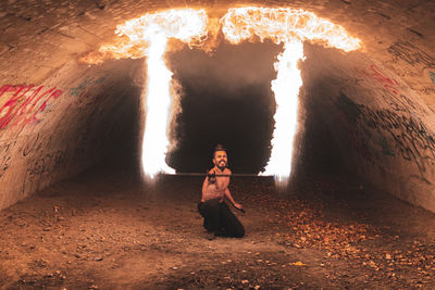Hipster male with fire staff performing skill in tunnel