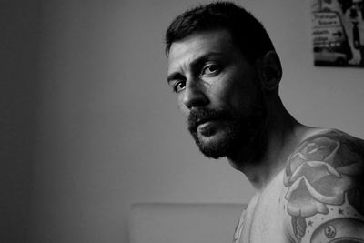 Portrait of shirtless man against wall at home