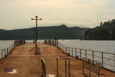 Pier on sea by mountains against sky