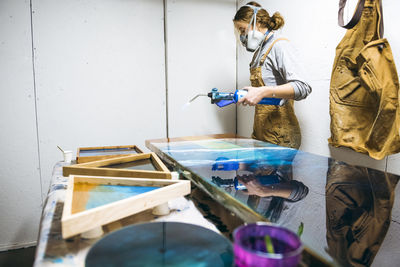 Female resin working in homemade studio with blowtorch