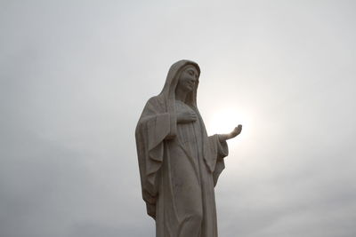 Low angle view of virgin mary statue against sky