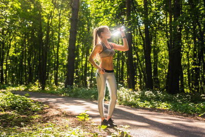 Full length of young woman standing in forest