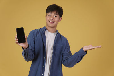 Portrait of smiling boy standing against orange background