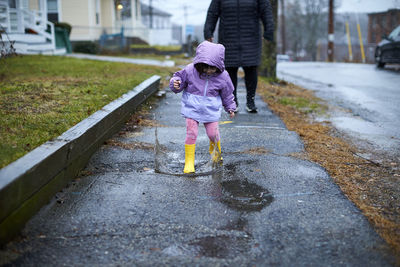 A little girl having fun splashing in puddles on a rainy day.